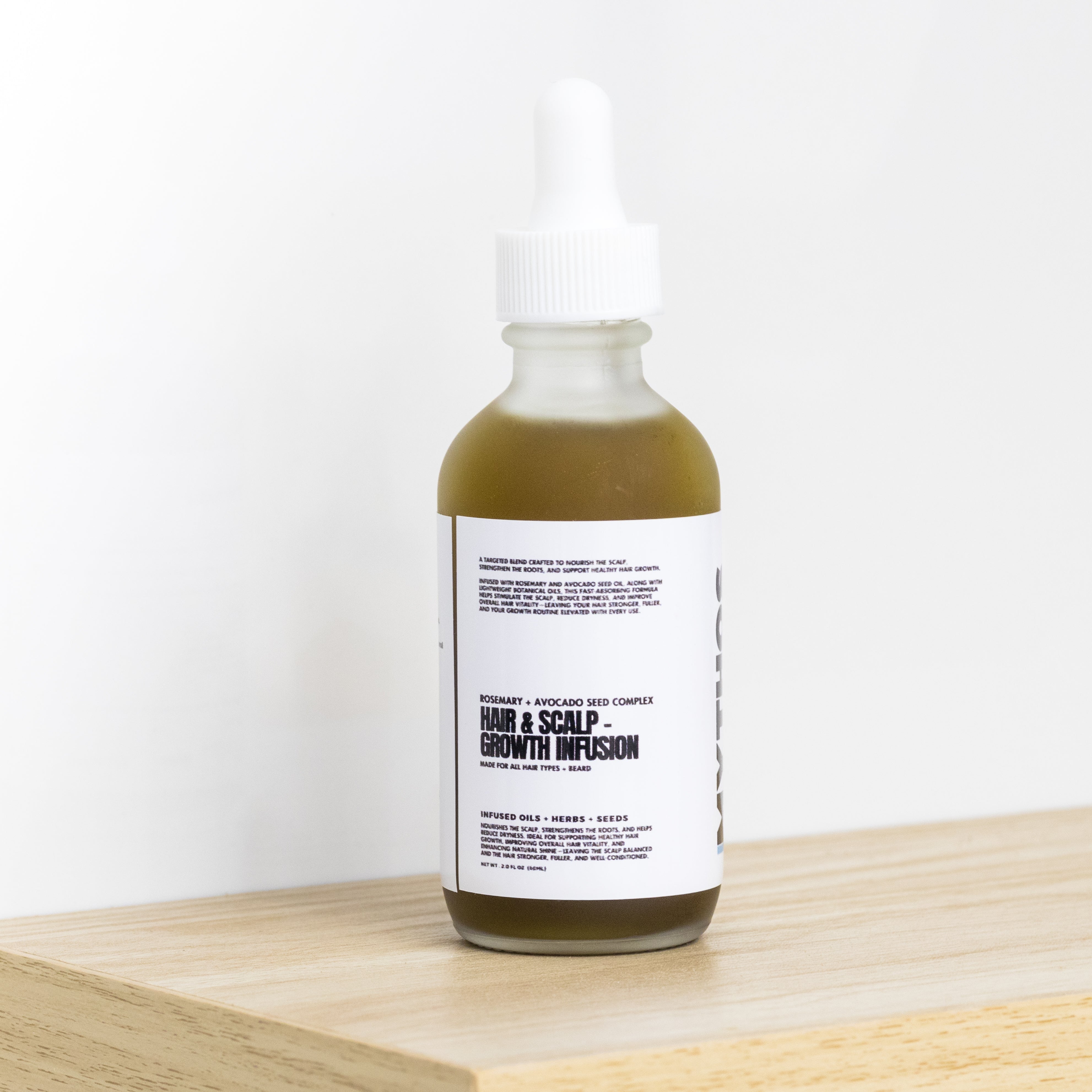 Bottle of hair and scalp growth infusion on a wooden surface with a white background